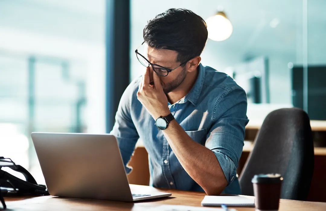 Stressed, tired and frustrated business man with headache at laptop.